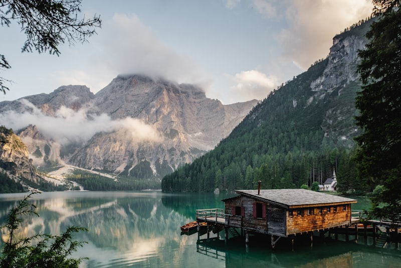 A calm alpine lake reflecting mountains under a clear sky on a hiking trail
